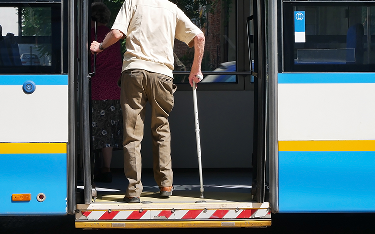 Elderly man boarding bus with cane